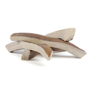 four giant moose split antler chews in a pile on a white background