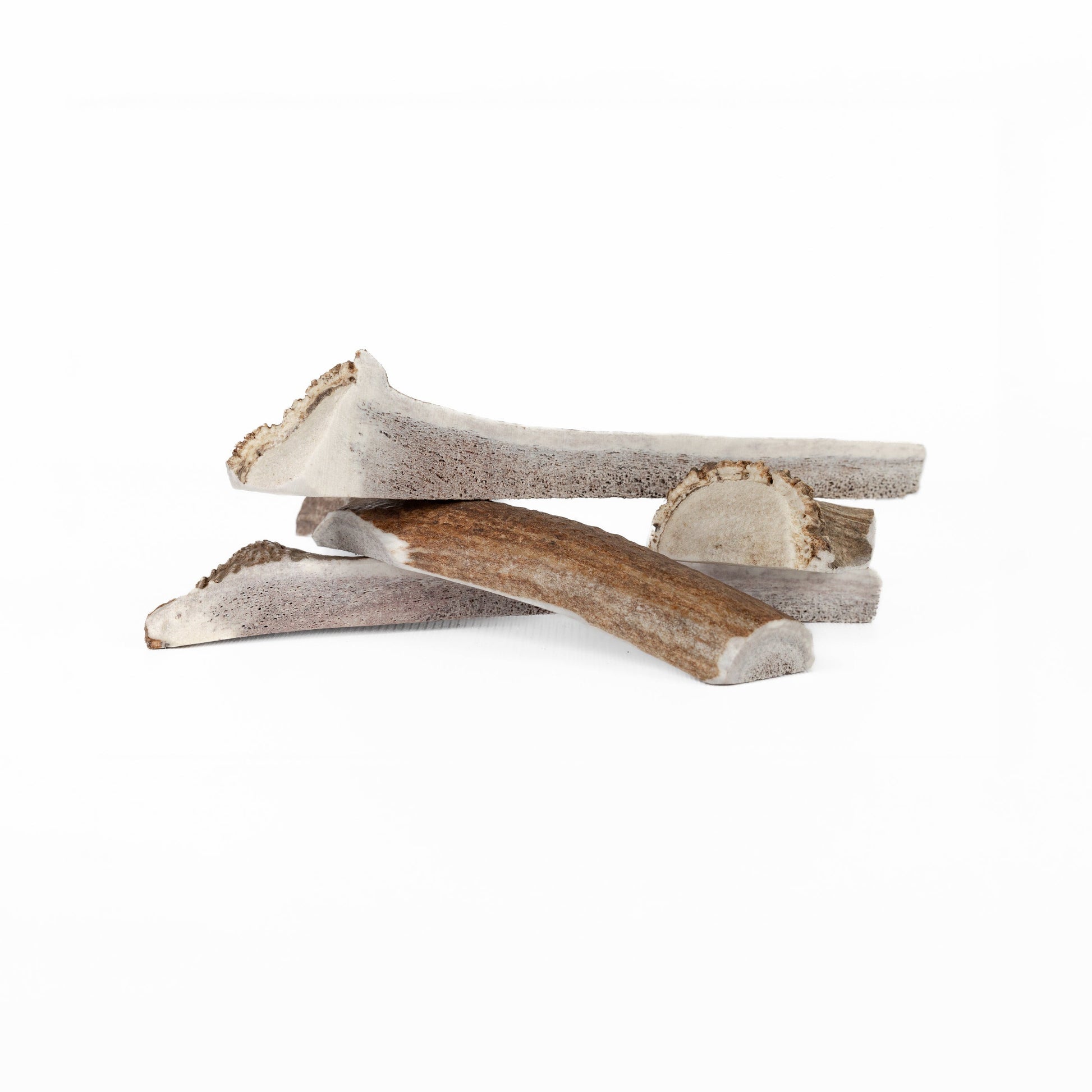 four large split and quarter split elk antler chews in a pile on a white background